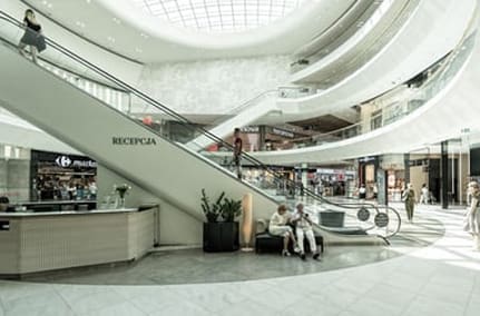 The inside of a shopping mall with people walking around.