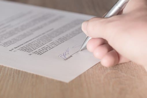 A Person Signing on a Piece of Paper With a Pen