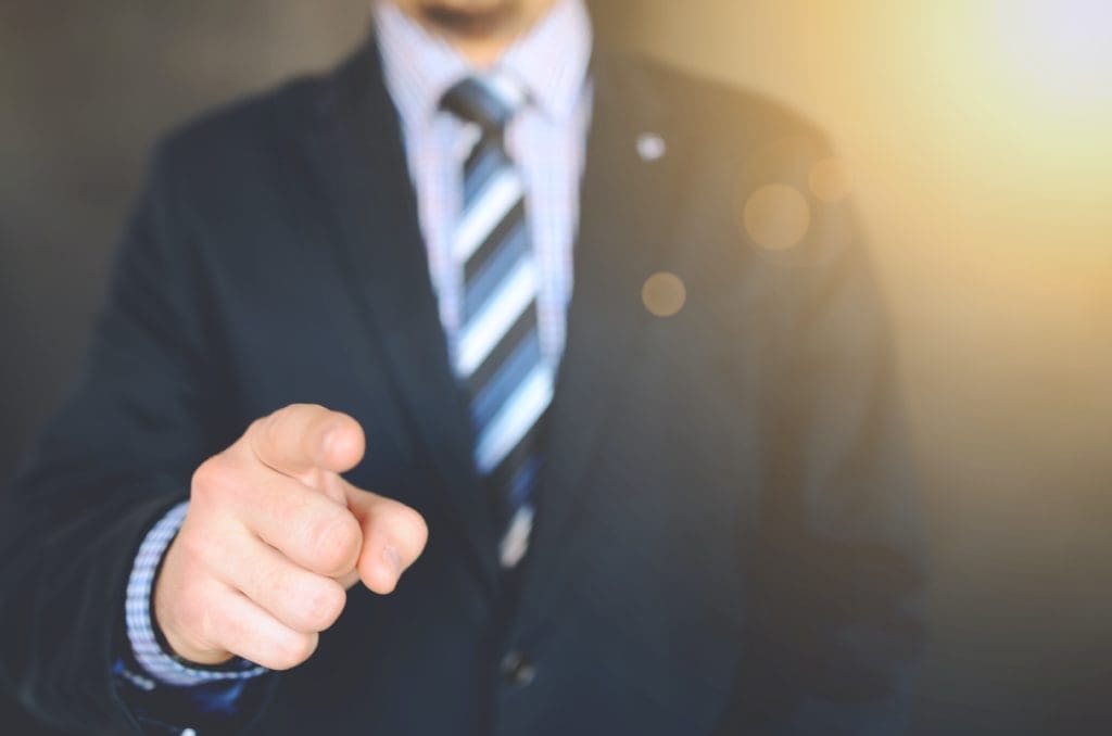 Man in suit pointing finger at viewer.