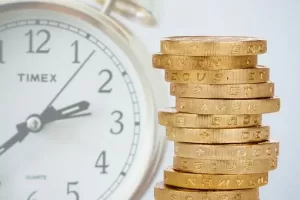 Image of a stack of gold coins next to a clock depicting how waiting to report stolen money can cost you and how Schlanger Law Group can help