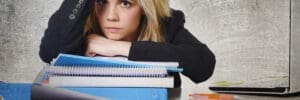 Woman with blonde hair resting on books.